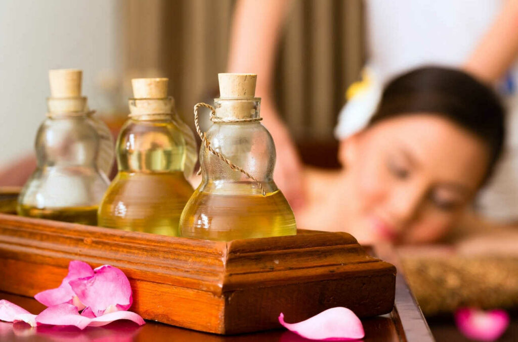 3 flacons huiles essentielles pour massage shiatsu et une femme massée avec les yeux fermés