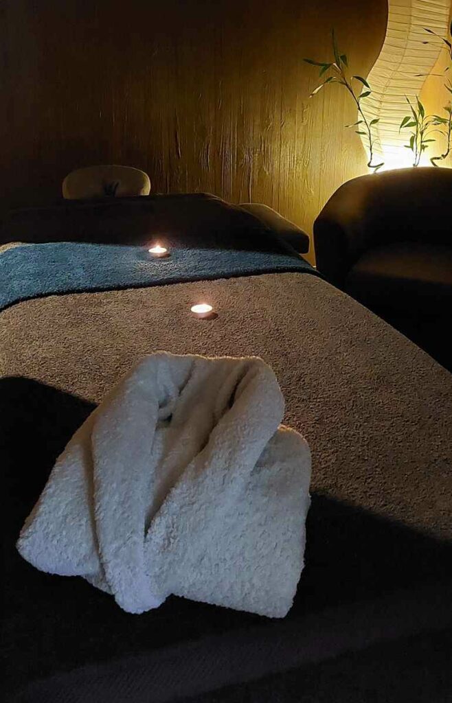 Spa à Mulsanne avec table à massage, bougies, bambou et serviettes pour un moment de pur plaisir