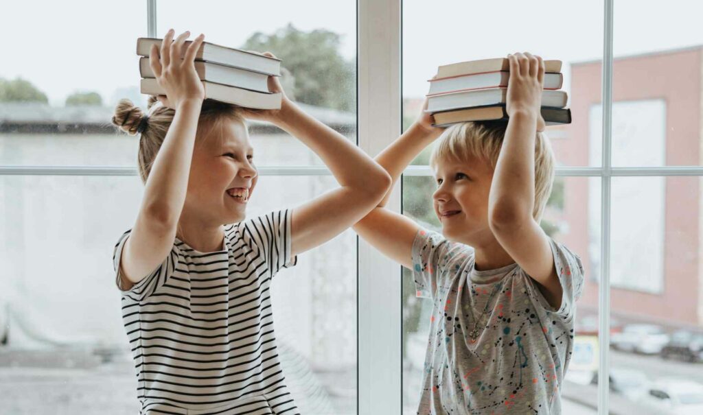 2 enfants (un garçon et une fille) tiennent des livres et sont heureux suite à un massage de tête pour le dos